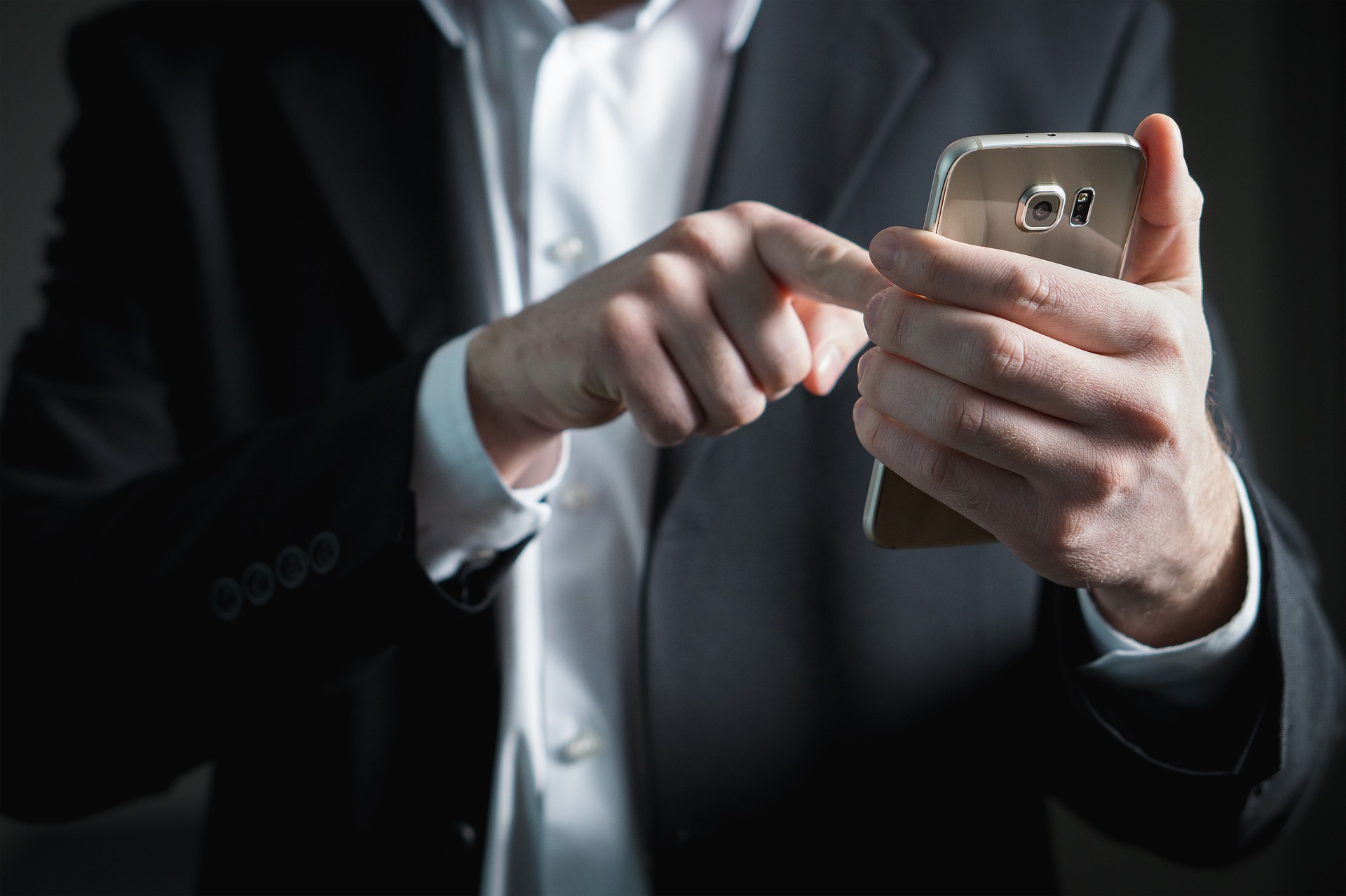 A man in a suit uses a smartphone
