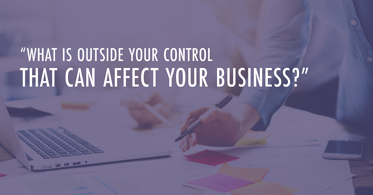 An employee works at a desk filled with papers and a laptop while text reads, "What is outside your control that can affect your business?"
