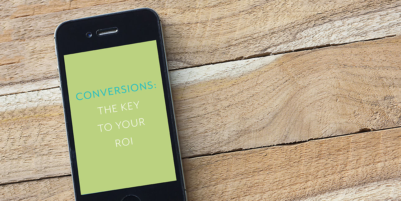 An iPhone reads, "Conversions: The Key to Your ROI"