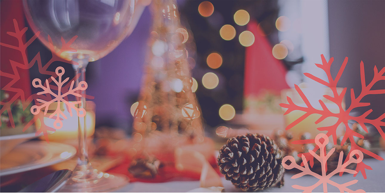 A pinecone, wine glass, and other festive winter decor sit on a decorated table