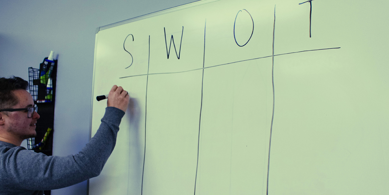 Kayden Grinwis does a SWOT analysis on a large piece of paper in the 8THIRTYFOUR office.