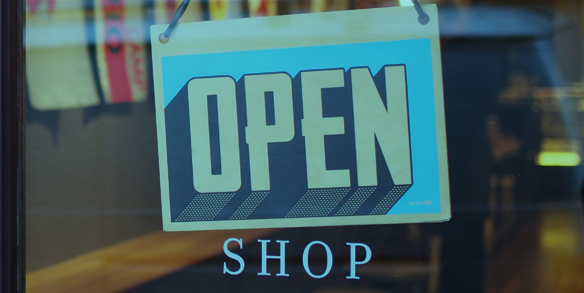 A store sign with an "Open Shop" sign hanging.