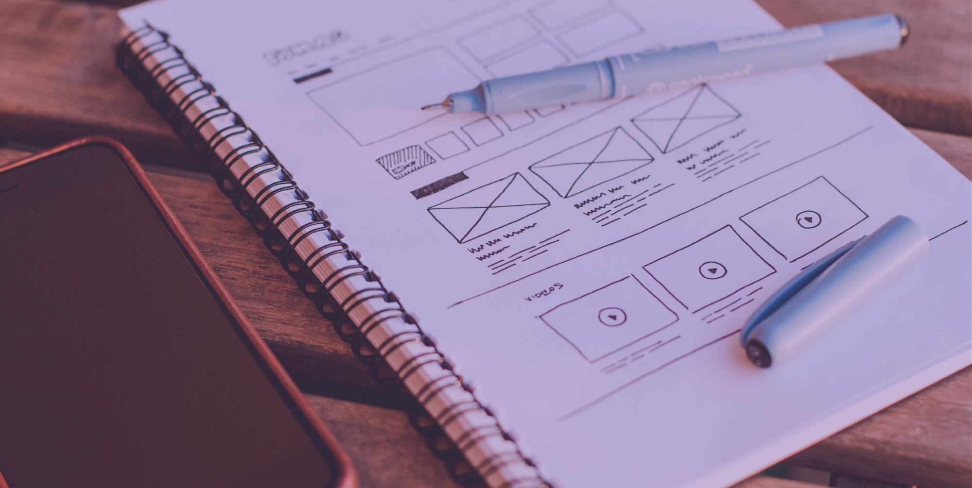 An image of a notebook with a website wireframe