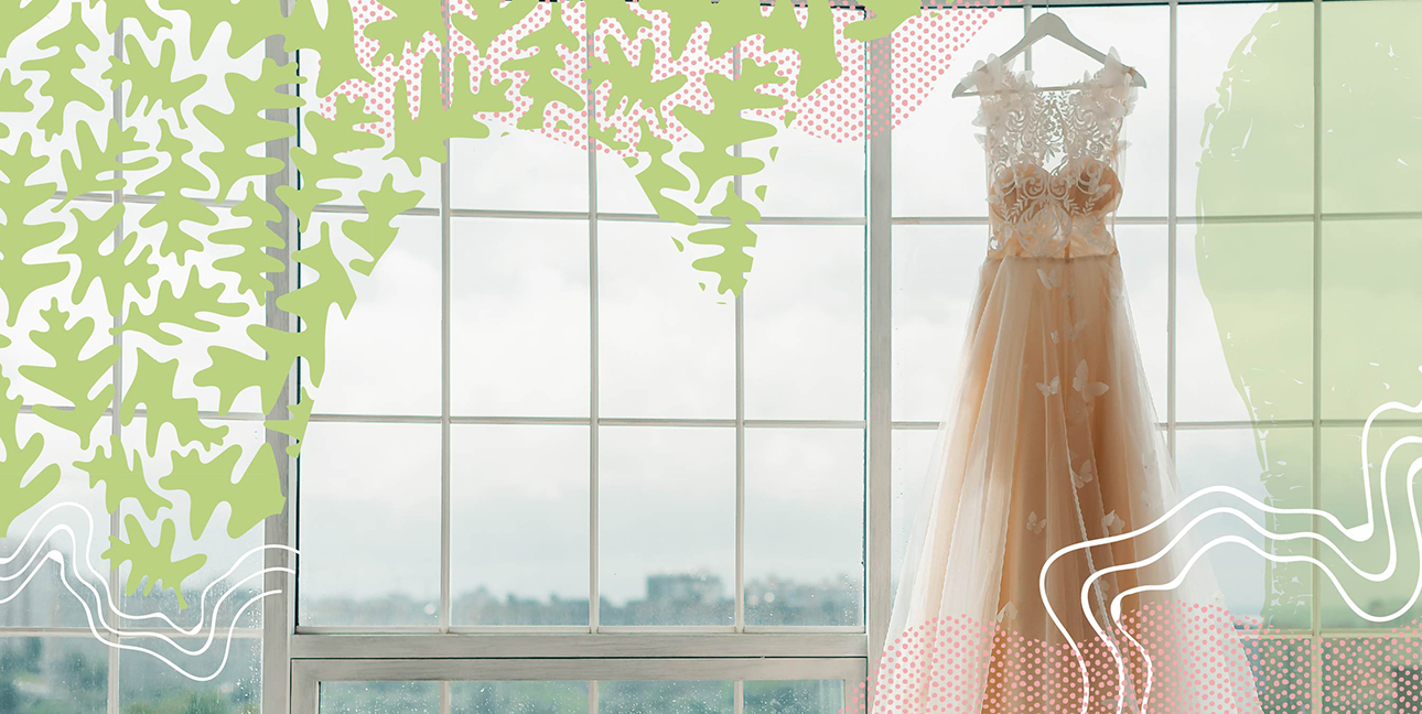A wedding dress hanging in front of a large window covered in windowpanes.