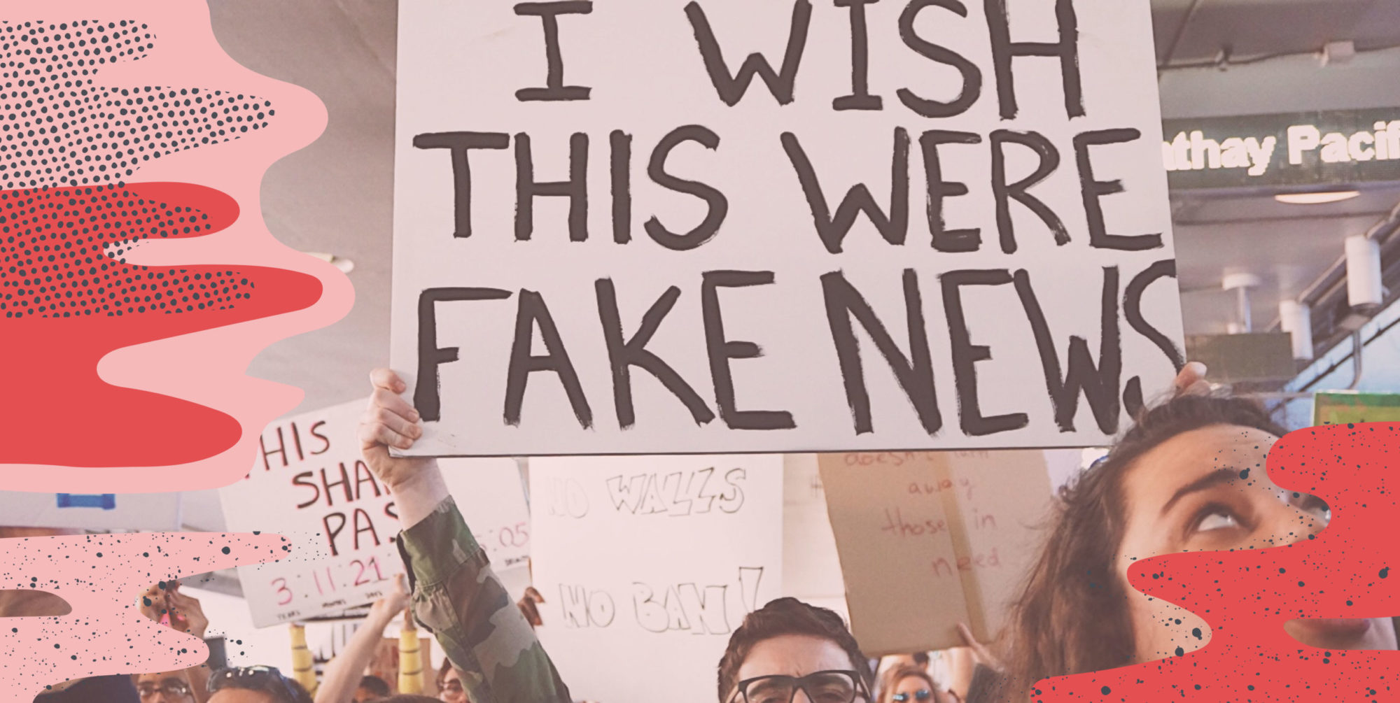 A person standing in a crowd holding a sign that says, " I wish this were fake news"