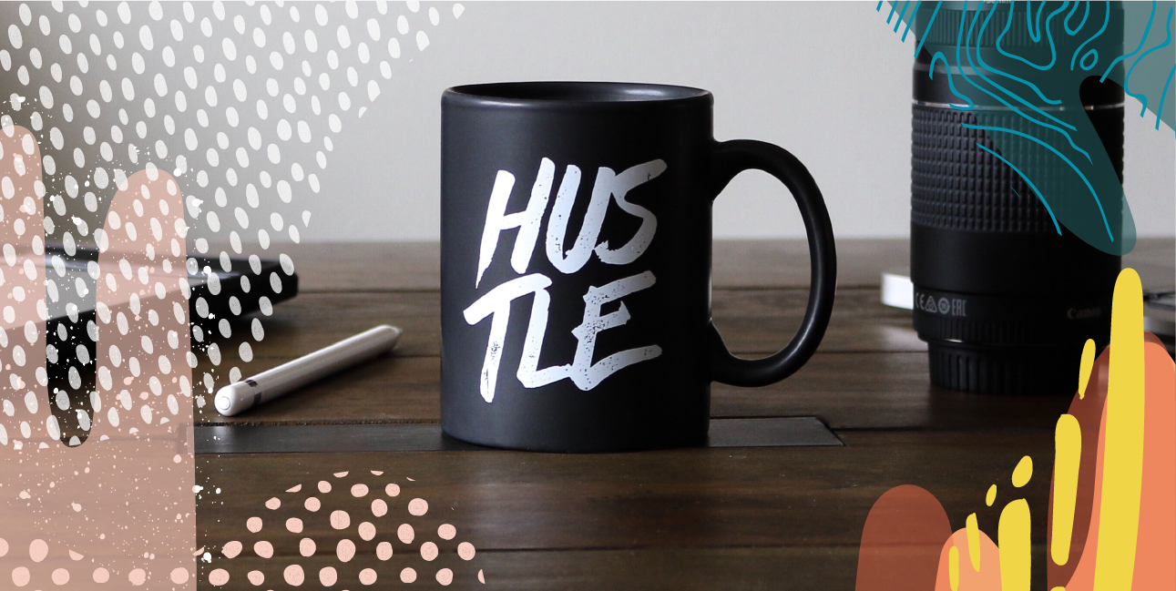 A black mug that says "Hustle" sitting on a table.